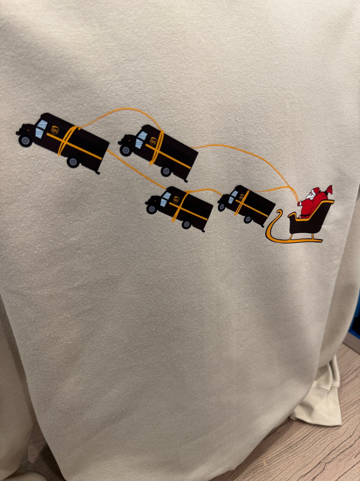 UPS Santa Peak Season Christmas crewneck sweater with Santa in a sleigh pulled by UPS trucks, screen-printed on soft, breathable fabric.