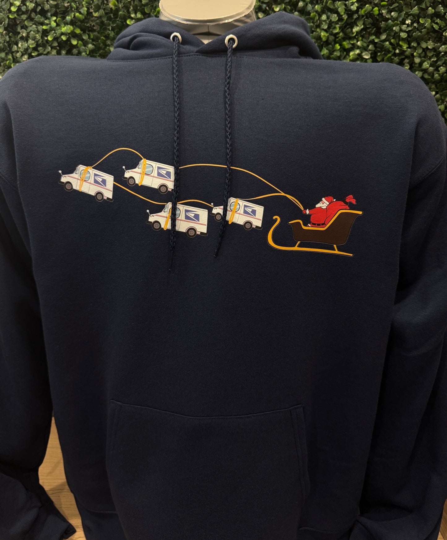Navy blue hoodie with printed design of Santa being pulled by USPS trucks with logos. USPS Sweatshirt Hooded Hoodie. Peak Season Gift